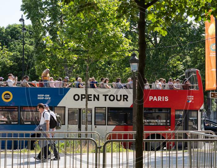 Open Tour Bus With French Flag Colors In Paris. Visitors On The Roof Top Of Sightseeing Bus At Sunny Day. Paris - France, 31. May 2019