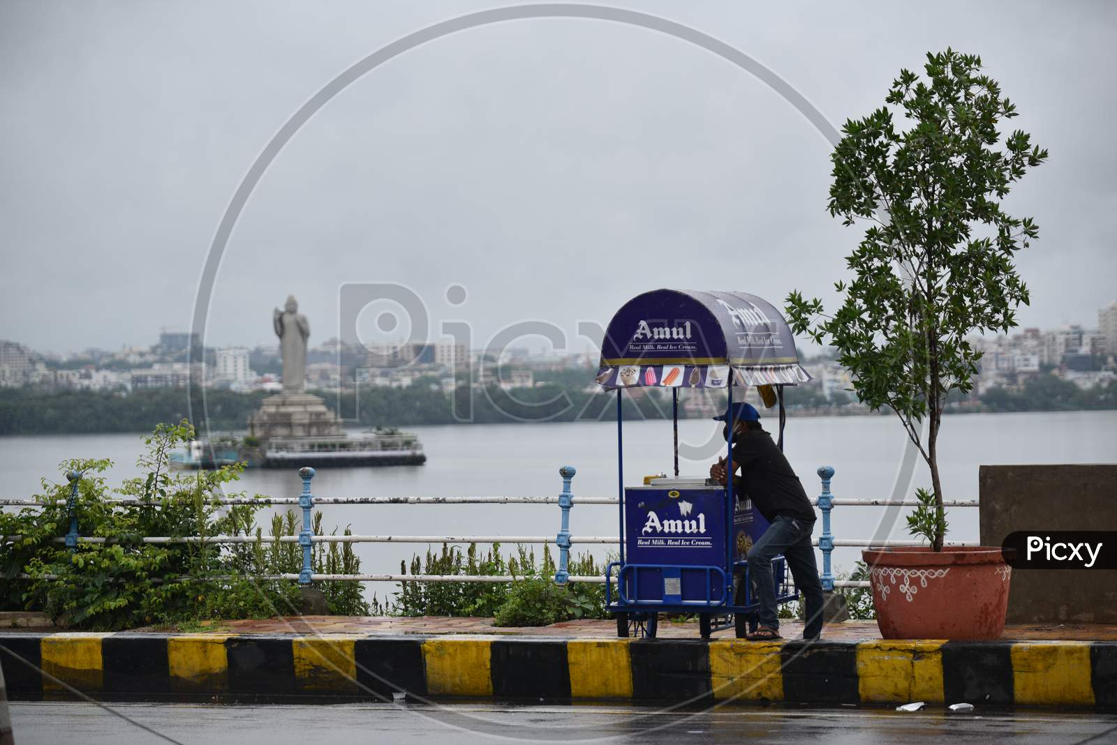 An Ice Cream vendor waits for customers as it rains at Tank Bund,Hyderabad, august 16, 2020.
