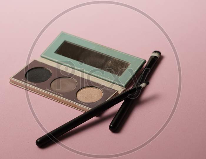 Makeup Kit With Brushes By Her Side On Pink Background.