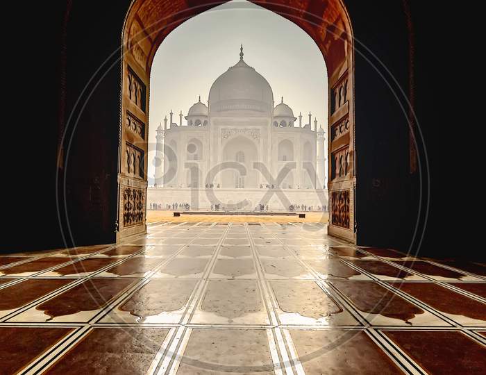 The white marble Taj Mahal building seen from inside the red stone mosque in Agra, India