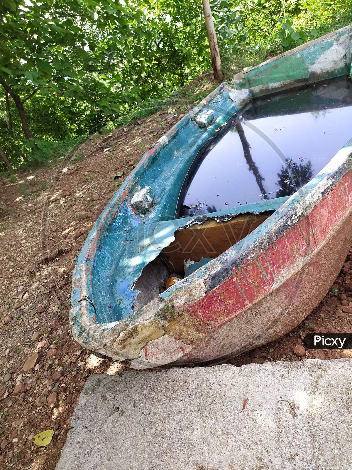 Old colourful wooden boat beside lake bank.