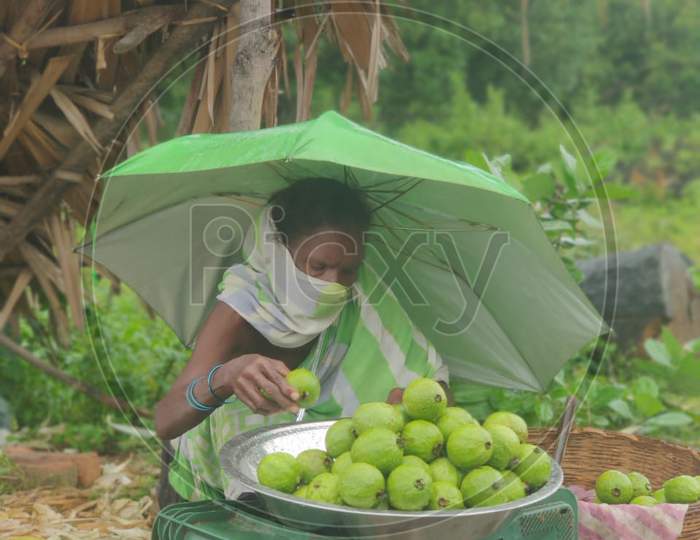 Poor Indian woman selling fruits on a rainy day in Corona crisis