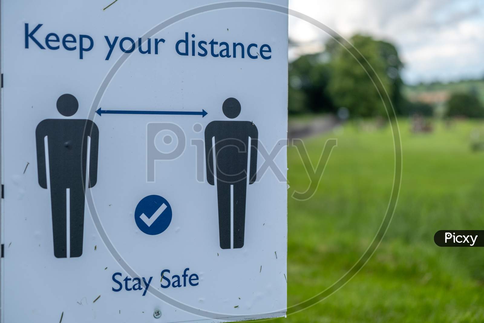 A Close Up Of A Sign In A Field Asking People To Socially Distance And Stay Safe At An Outdoor Event As The Coronavirus Lockdown Eases In England