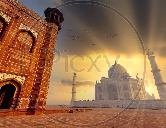 The white marble Taj Mahal building in golden light as seen from inside the red stone mosque in Agra, India