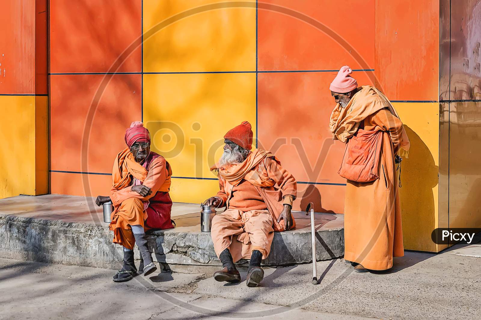 Sadhus in orange and yellow holy colours sitting in the winter sun outside a holy Hindu temple in Haridwar, northern India