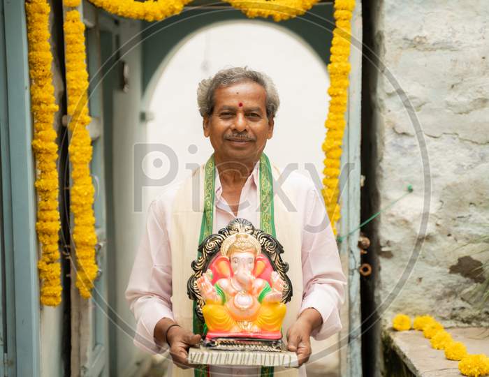 Happy Elder Man With Ganesha Idol Coming Home During Ganesha Or Vinayaka Chaturthi Festival - Concept Of Indian Religious Festival Celebration.