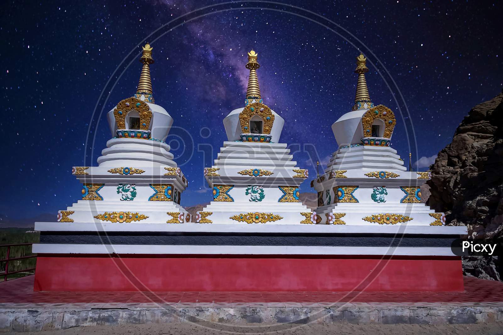 White painted stupas holding buddhist relics under a starry sky as seen at the Thikse Monastery near Leh city, Ladakh, India