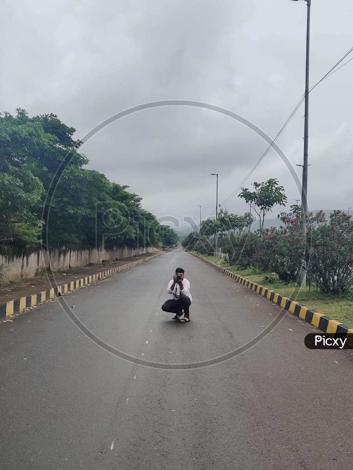 A photographer clicking a photo on an empty Road on a cloudy day in India