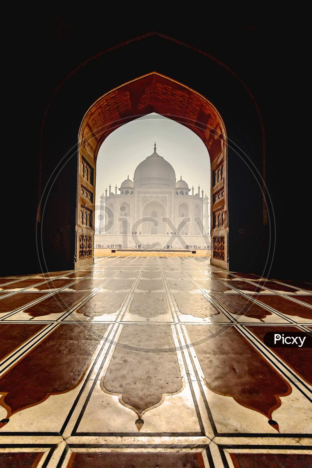 The white marble Taj Mahal building seen from inside the red stone mosque in Agra, India