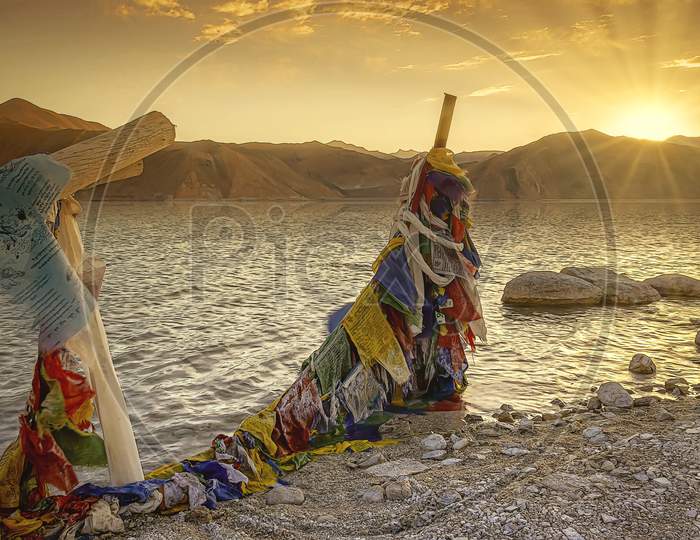 Frozen Tibetan colorful Prayer flags in the golden sunrise on the banks for Pangong Tso Lake in Northern India