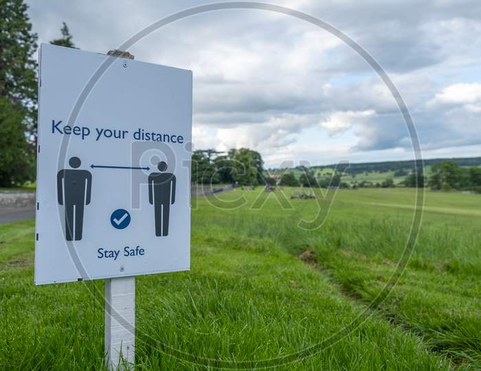 A Sign In A Field Asking People To Socially Distance And Stay Safe At An Outdoor Event As The Coronavirus Lockdown Eases In England