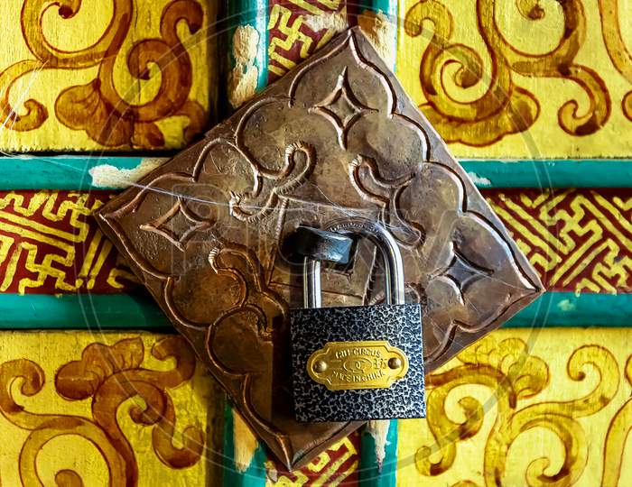 A Chinese lock on a beautiful Tibetan buddhist yellow decorated door in Thikse Gompa, Ladakh, India