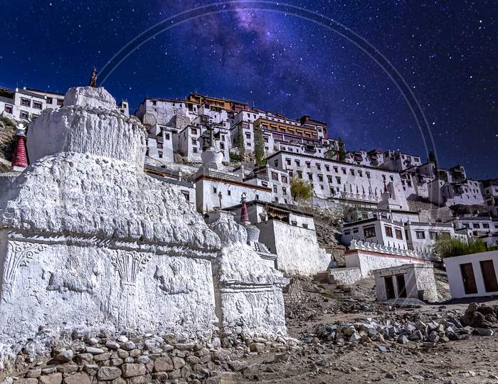 Seen from the Thiksey village you see white painted stupas holding buddhist relics under a starry sky as seen at the Thikse Monastery near Leh city, Ladakh, India