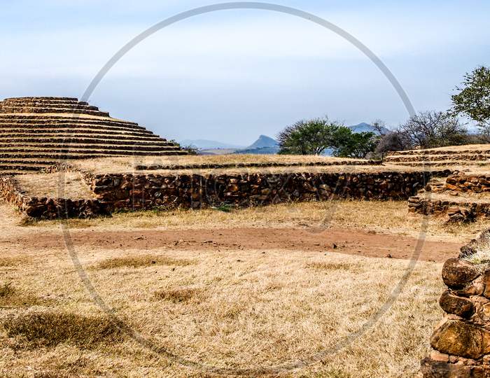 Stone Walls And A Circular Pyramid At The Pre-Hispanic Archaeological Site Of Guachimontones, Sunny Day With A Blue Sky In Teuchitlan In The State Of Jalisco, Mexico