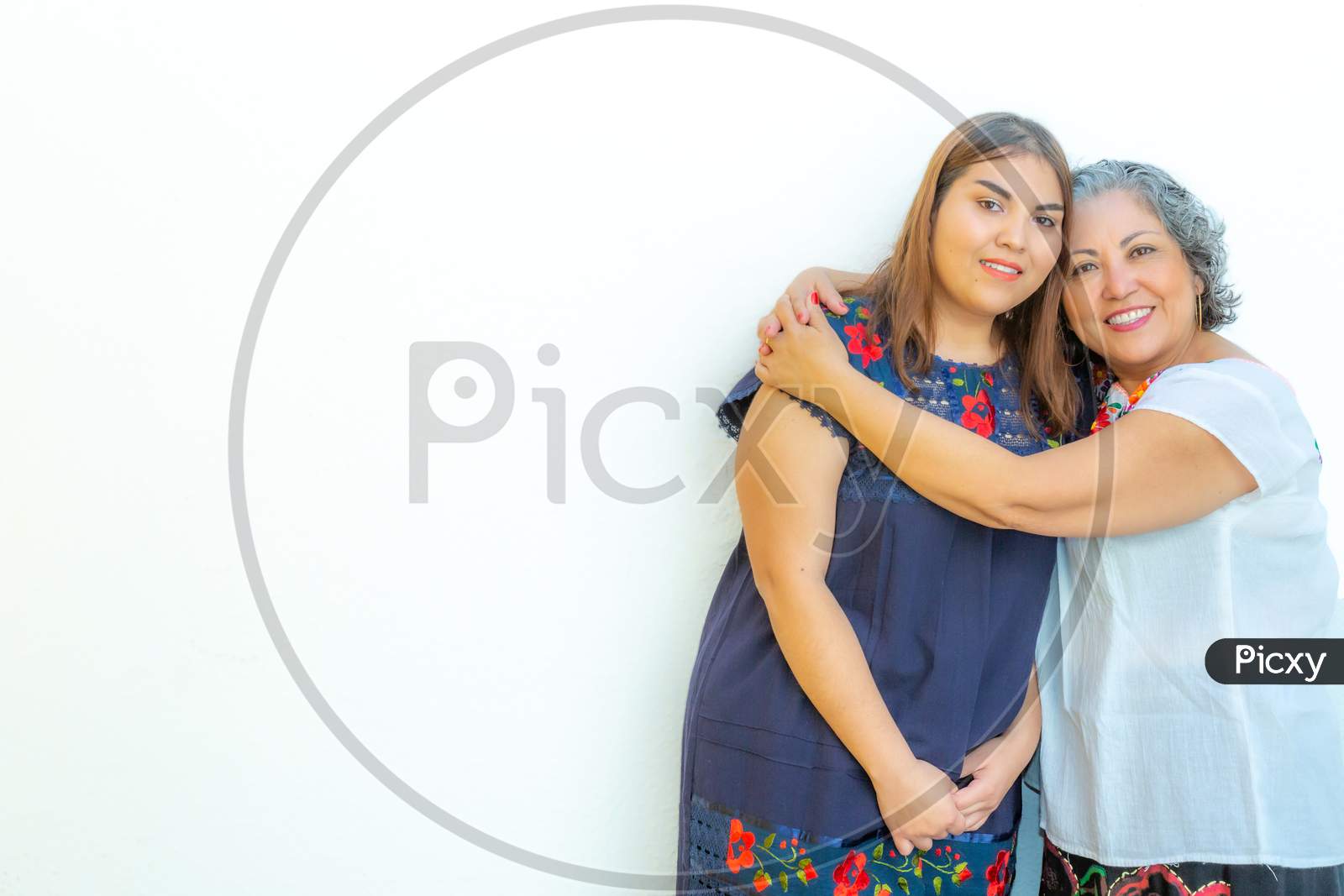 Mother Hugging Her Daughter With A Lot Of Love, Two Smiling Mexican Women On A White Background, Space For Text