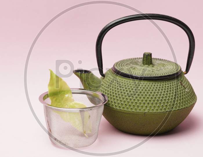 Tea Pot With Leaves On A Pink Background.