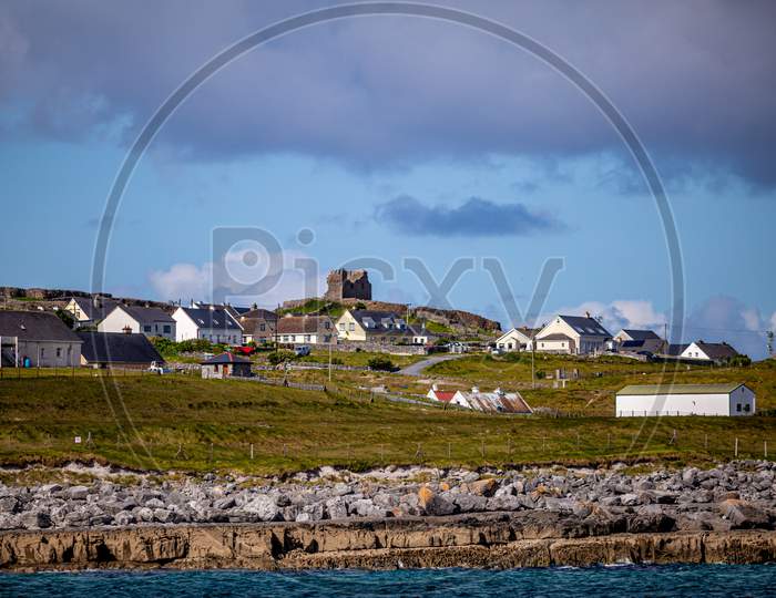 Beautiful View Of The Inis Oirr Island With Its Houses And The Ruined 15Th-Century Castle Tower In A Prehistoric Stone Fort In The Background, Wonderful Sunny Day In Aran Islands, Ireland
