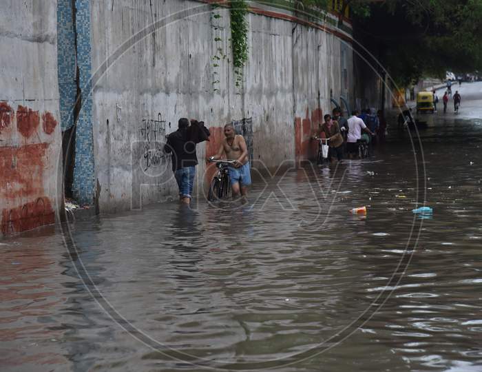 People cross a flooded street during heavy rains in New Delhi, India, August 19, 2020.