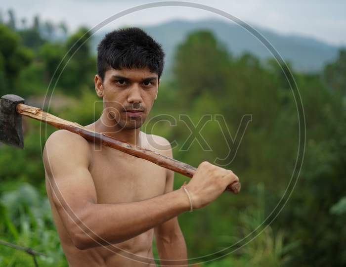 Young Handsome Shirtless Boy Holding Axe In His Shoulders.