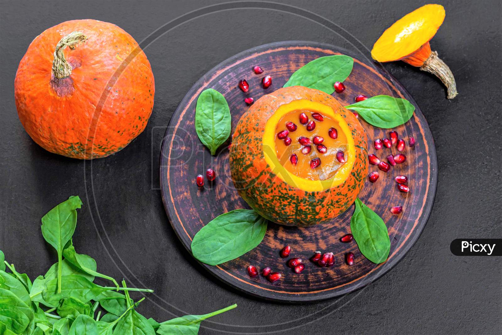 Top View Halloween Concept-Pumpkin With Pumpkin Puree, Spinach And Pomegranate On Black Background