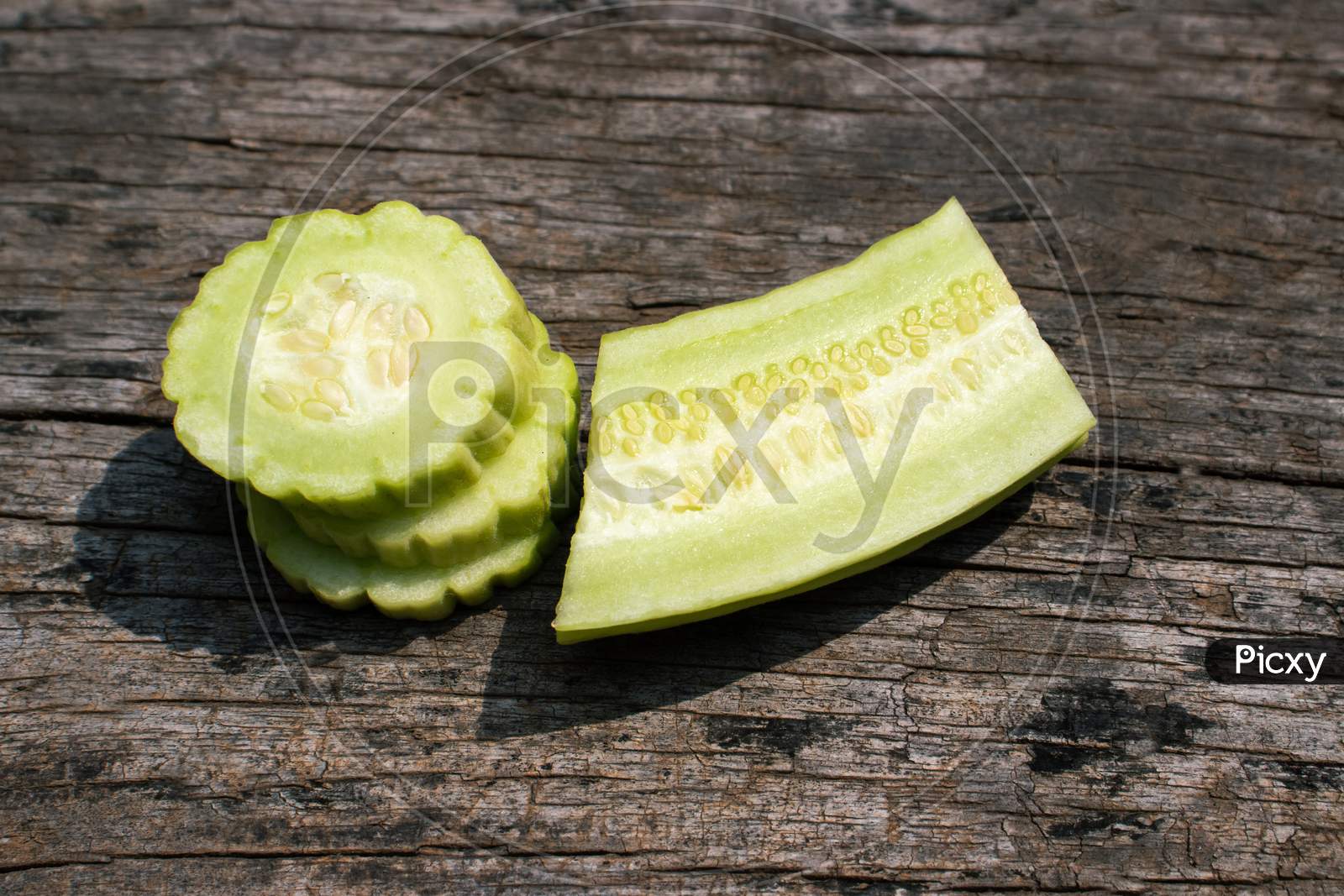 Armenian Cucumber Cuts Or Yard Long Cucumber Slices Isolated On Wooden Background, Also Known As Kakri