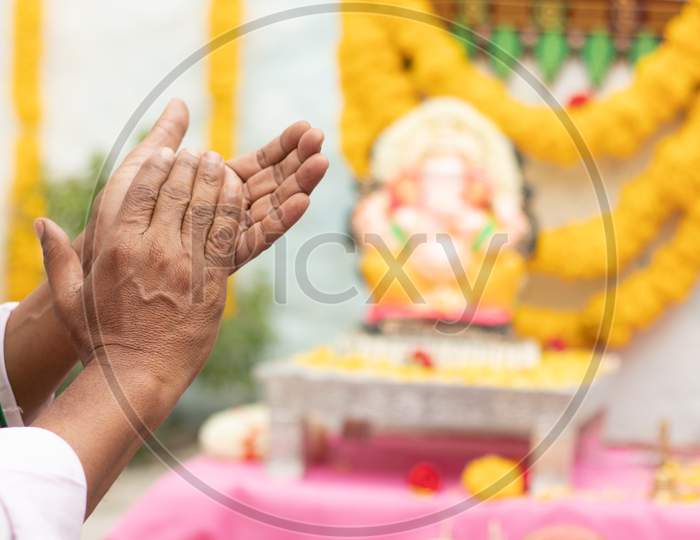 Close Up Of Elder Man Hands Offering Bhajan Or Hymn In Front Of Lord Ganesha Idol By Clapping During Ganesha Or Vinayaka Chaturthi Festvial Ceremony At Home.