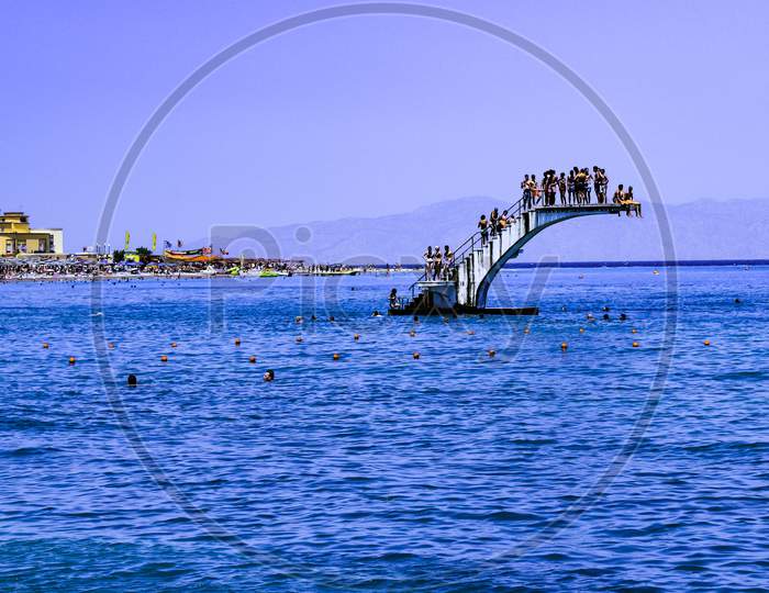 A Crowded White Dive Platform In The Middle Of The Blue Sea At Rhodes Island Greece During Summer Against The Clear Blue Sky