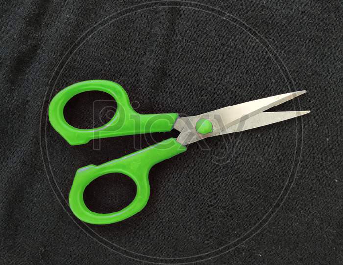 Closeup Of Steel And Green Color Small Single Scissor Isolated On Black Background