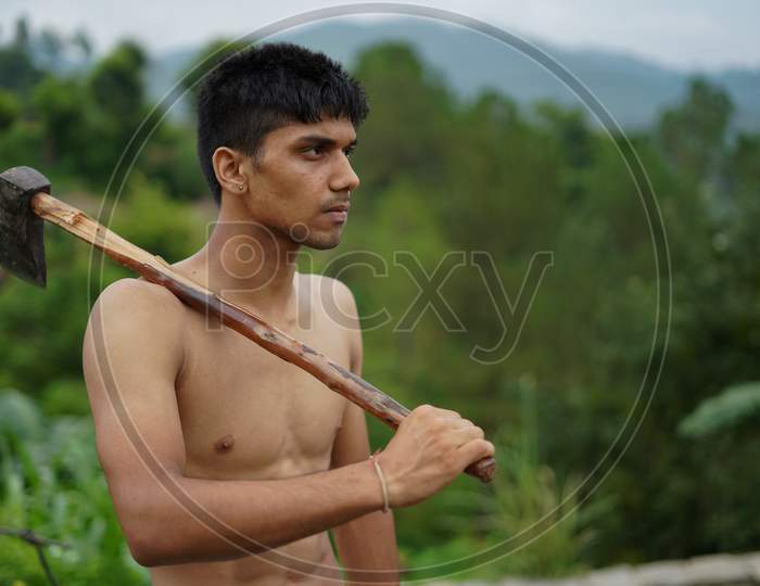 Young Handsome Shirtless Boy Holding Axe In His Shoulders.