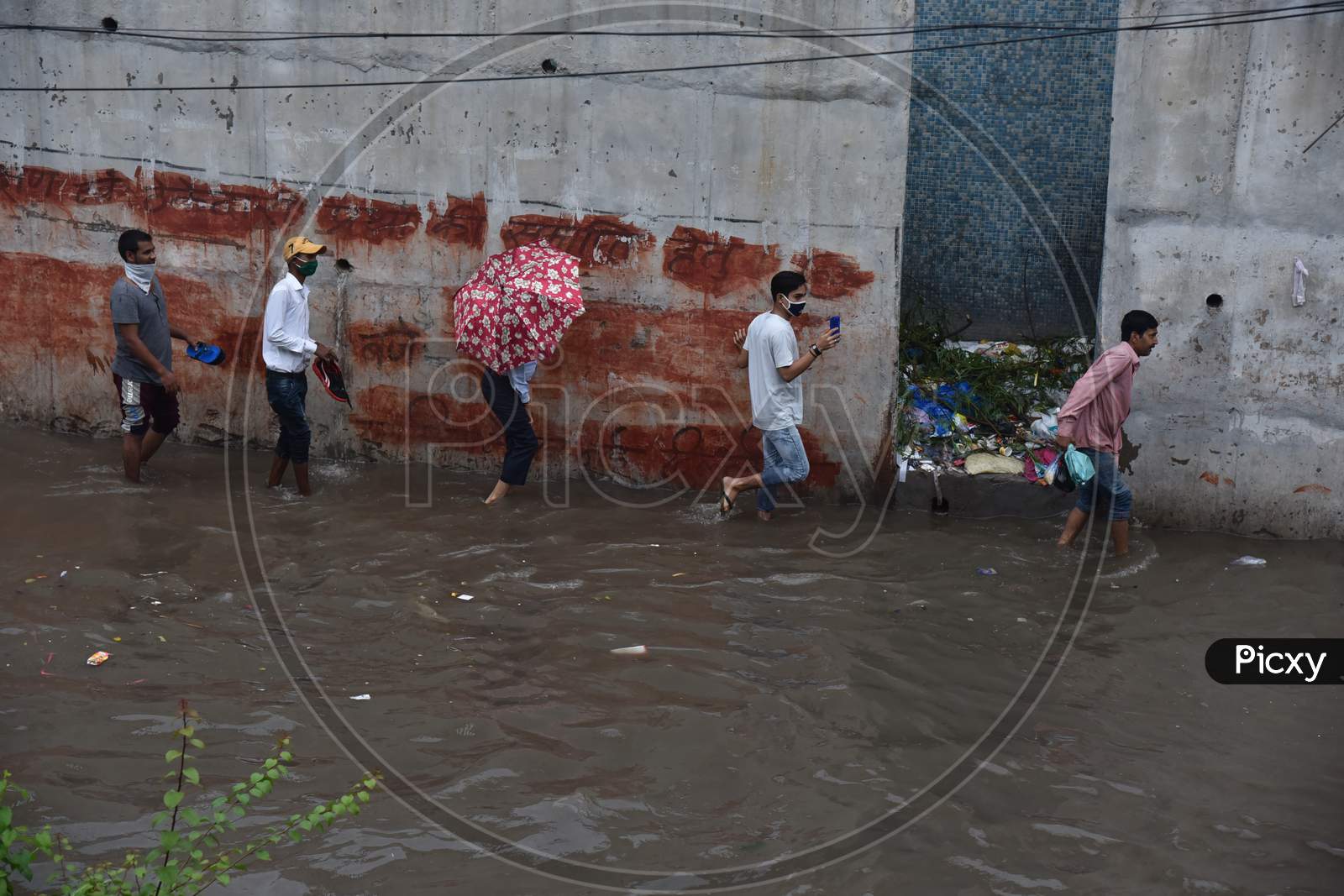 People cross a flooded street during heavy rains in New Delhi, India, August 19, 2020.