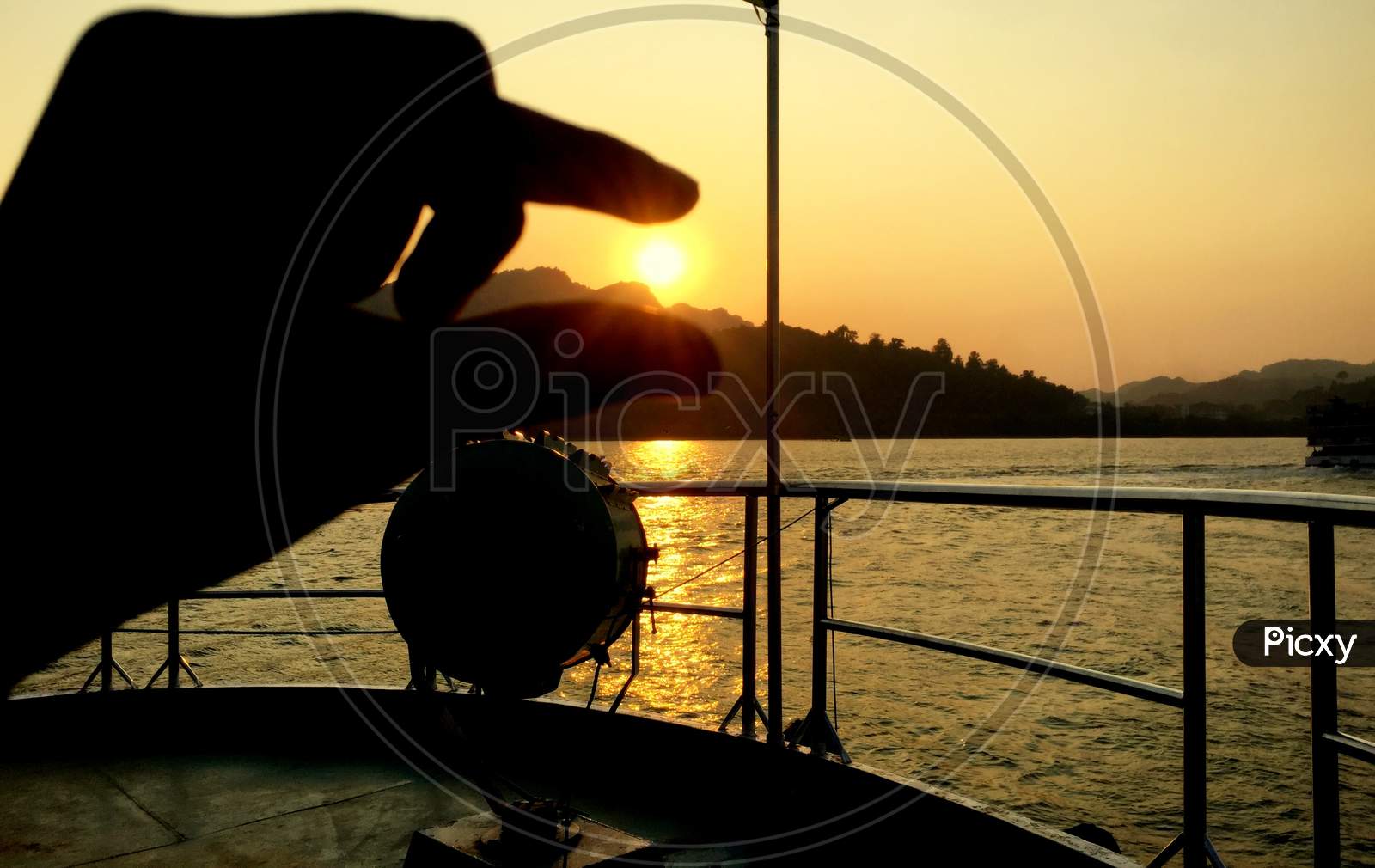 Summer Cruise Vacation Concept. Silhouette View Of The Sea With A Beautiful Sunset Just Above The Horizon Touch The Sun With Finger .