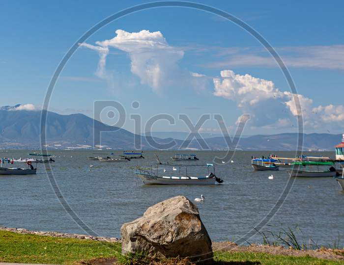 Chapala, Jalisco / Mexico, January 20Th, 2020. Chapala Lake With Motor Boats And Pelicans On The Calm Waters With Mountains In The Background, Sunny Day In The State Of Jalisco, Mexico