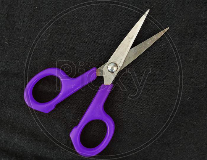 Steel And Purple Color Small Single Scissor Isolated On Black Background