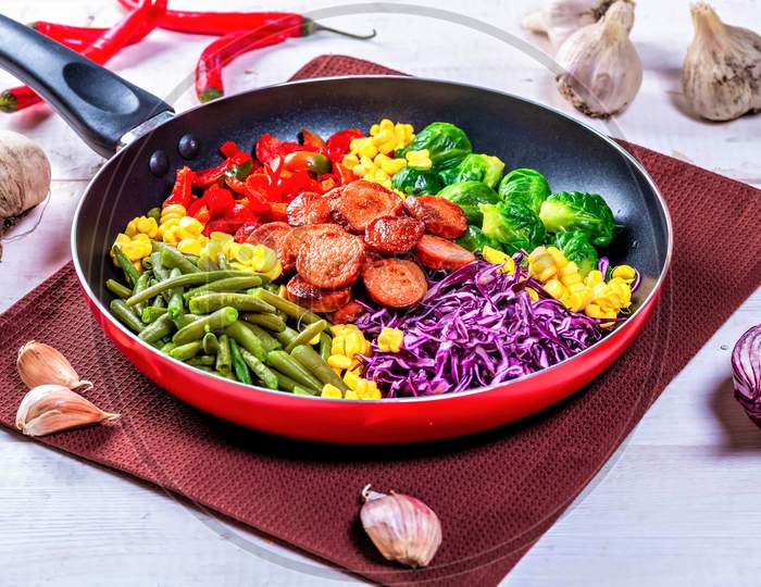 Asparagus, Brussels Sprouts, Corn, Peppers And Sausages In A Frying Pan