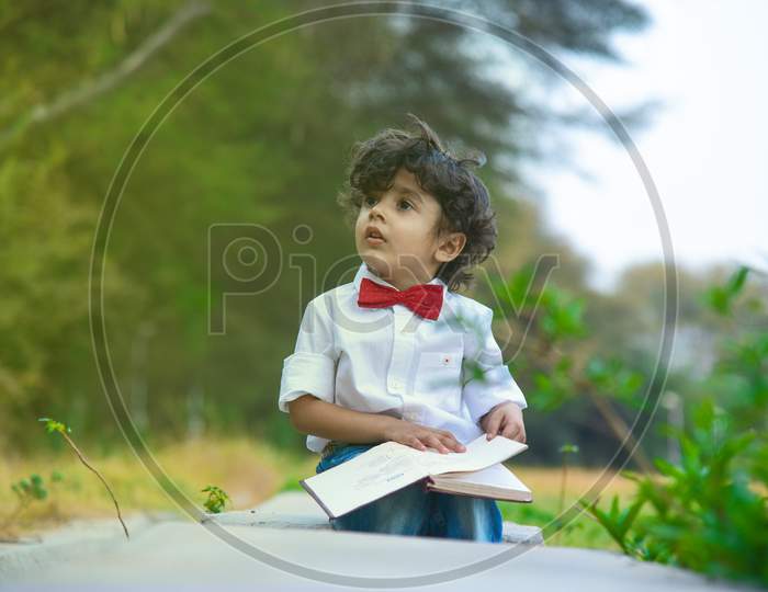 Portrait Of Cute Young Fashionable Boy Posing With Book Outdoors.