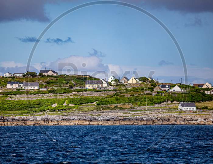 Beautiful View Of The Inis Oirr Island With Its Houses Seen From A Boat On The Calm Blue Waters Of The Atlantic Ocean, Wonderful Sunny Day In The Aran Islands, Ireland