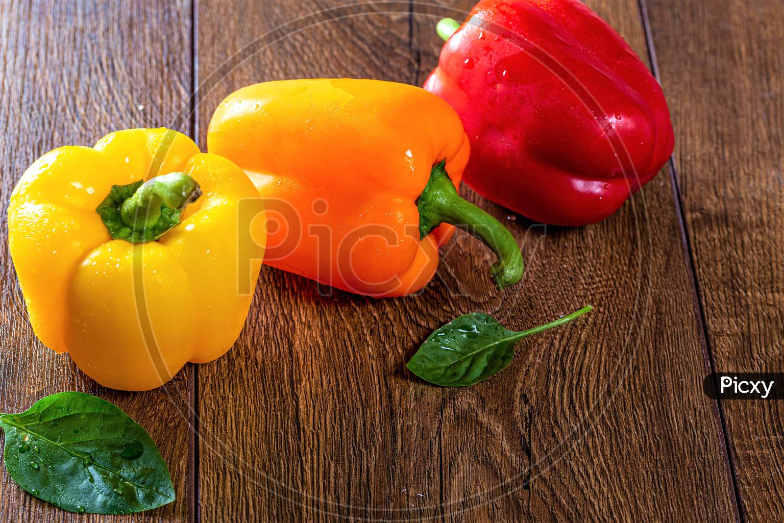 Bell Pepper With Green Leaves On A Brown Wooden Background