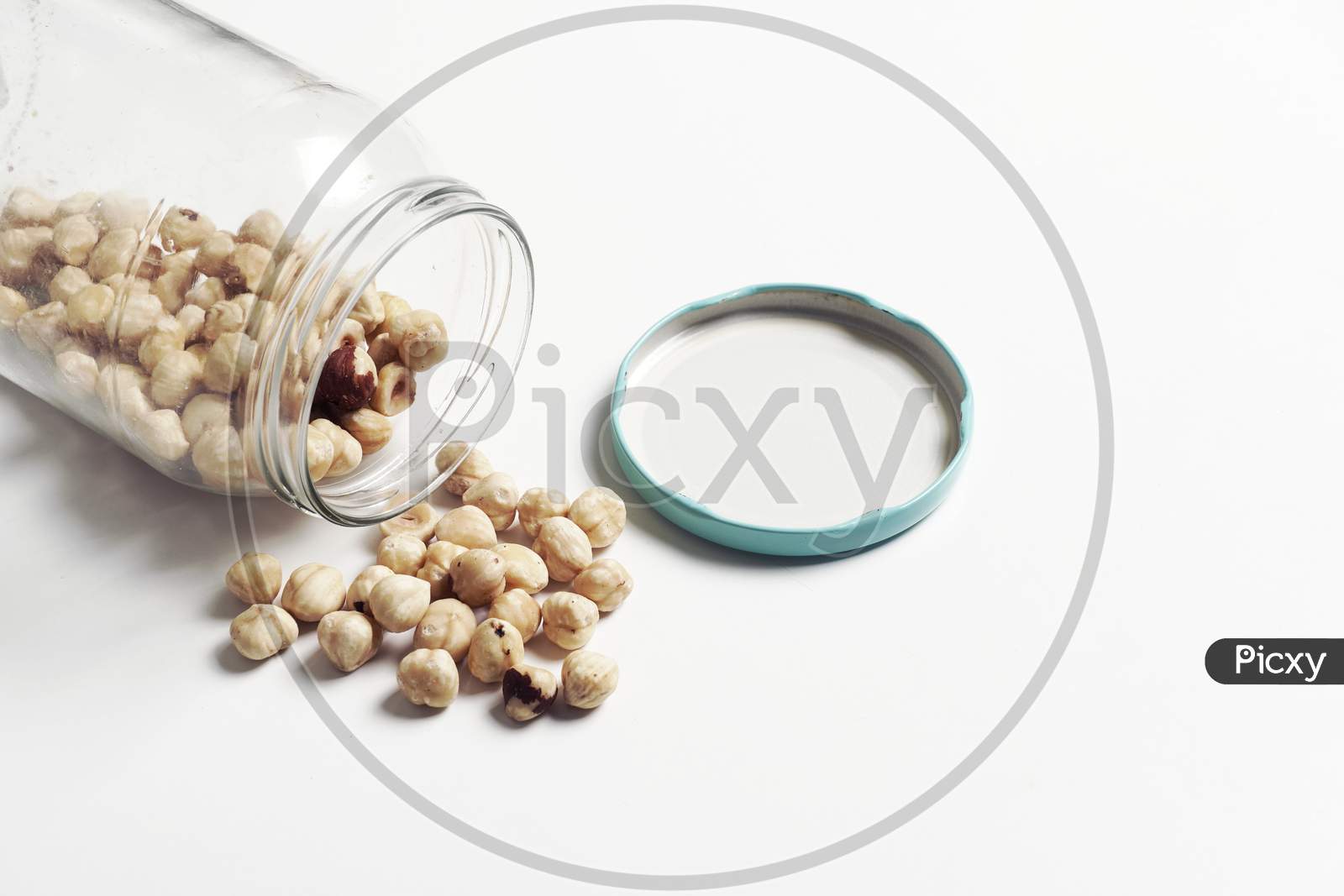 Chickpeas Spilling From A Glass Jar On White Background.