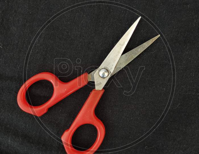 Steel and Red Color Small Single Scissor isolated on black Background