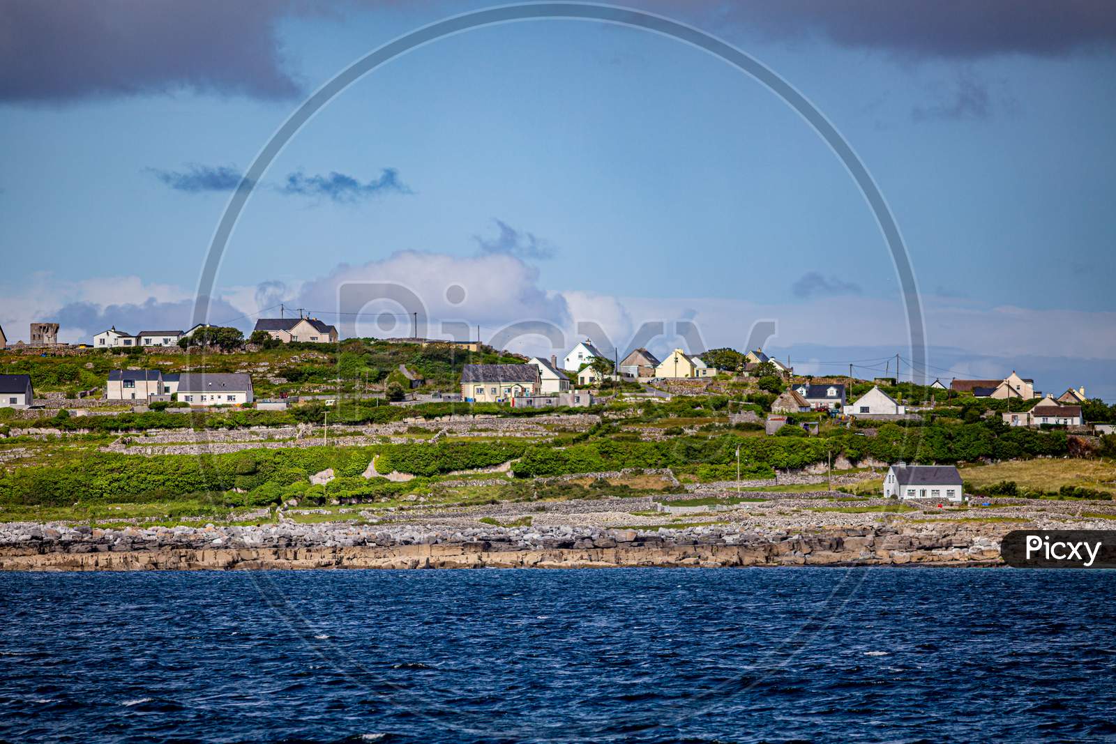 Beautiful View Of The Inis Oirr Island With Its Houses Seen From A Boat On The Calm Blue Waters Of The Atlantic Ocean, Wonderful Sunny Day In The Aran Islands, Ireland