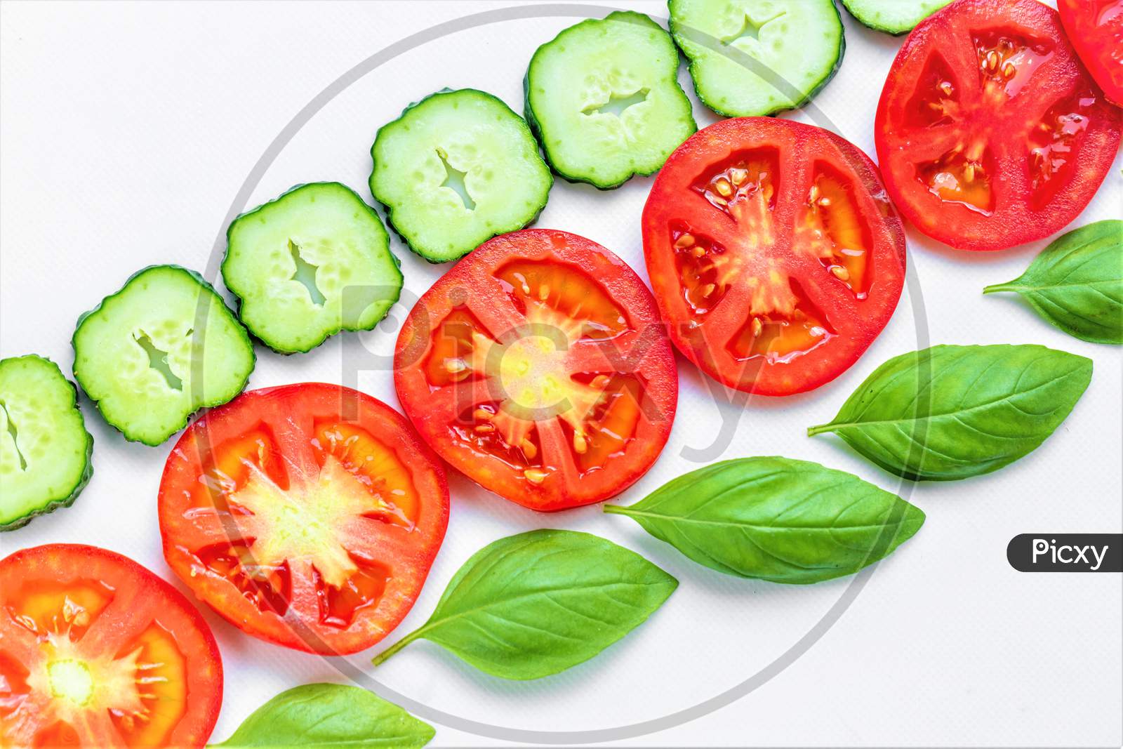 Round Pieces Of Cucumber, Tomato And Basil Leaves. Top View
