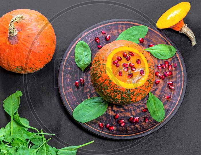 Top View Halloween Concept-Pumpkin With Pumpkin Puree, Spinach And Pomegranate On Black Background