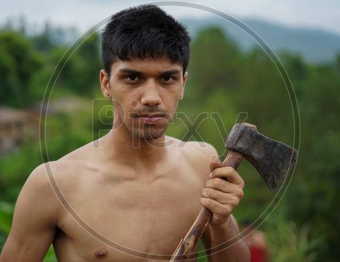 Young Handsome Shirtless Boy Holding Axe In His Hands.