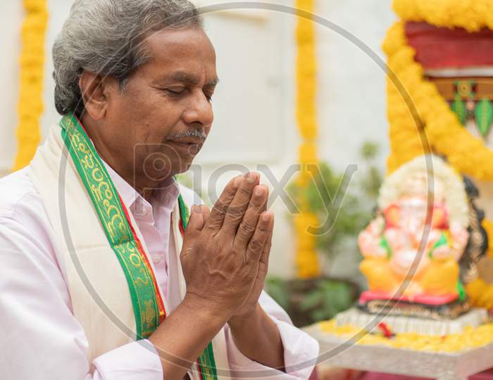 Elder Man Offering Bhajan Or Hymn In Front Of Lord Ganesha Idol During Ganesha Or Vinayaka Chaturthi Festvial Ceremony At Home.