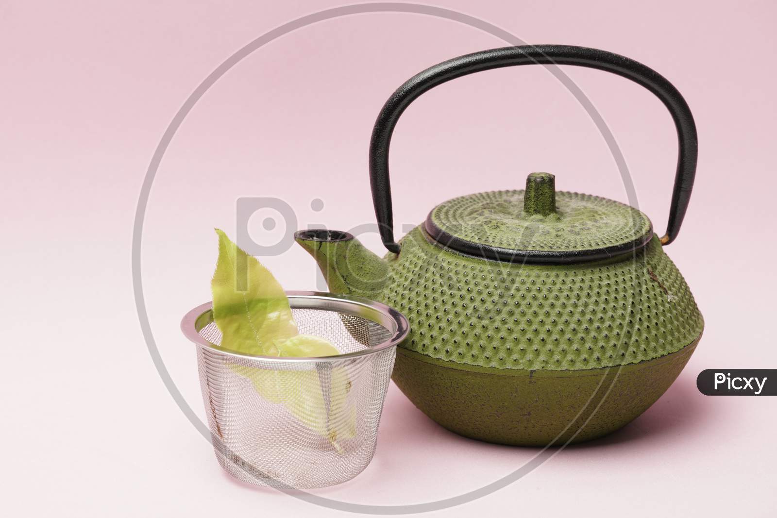 Tea Pot With Leaves On A Pink Background.