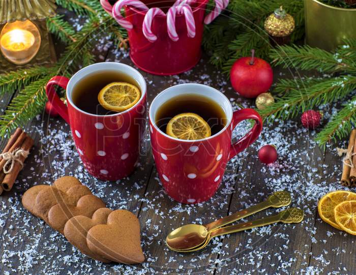 Christmas Tea, Cookies, Lemons, Mug, Heart Cookies On Decorations Table. New Year Celebration On Christmas. Christmas Sweet On Table. Christmas Candy Sticks In Red Tub 4K Image.