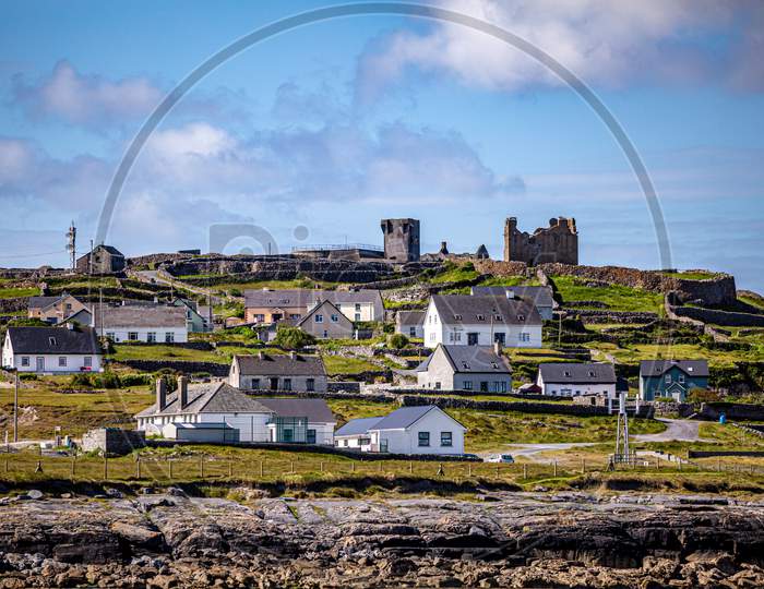 Beautiful View Of The Ruined 15Th Century Castle In A Prehistoric Stone Fort And Houses On The Inis Oirr Island Seen From A Boat, Wonderful Sunny Day In The Aran Islands, Ireland
