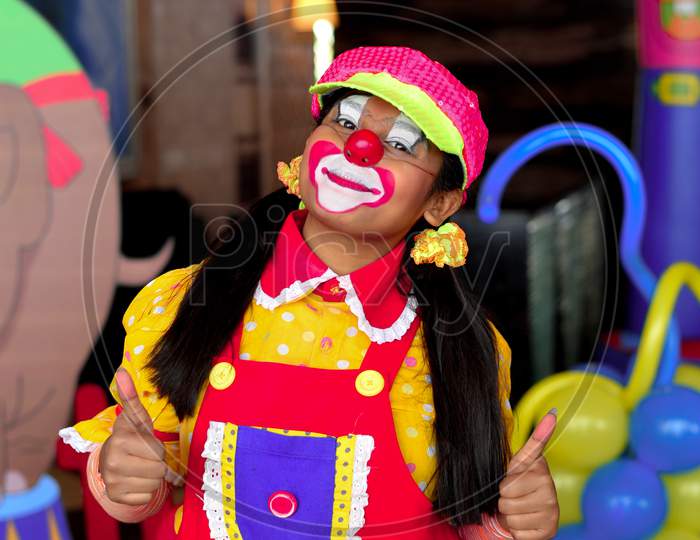 A female clown facing a camera and smiling pose