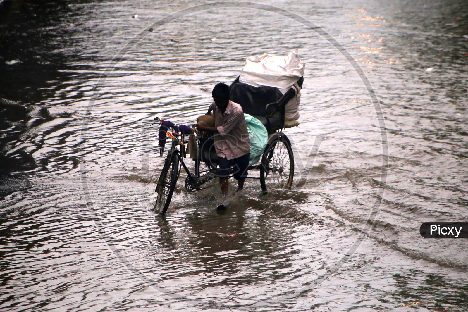 A rickshaw puller wades through a flooded road during heavy rains in Ajmer, On August 1, 2020.