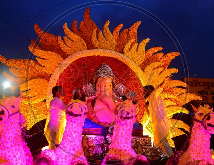 An idol of lord Ganesh beautifully decorated with flowers and lights